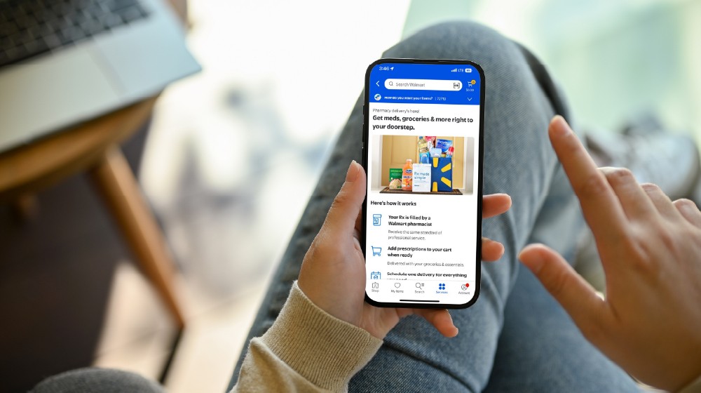Photo of a customer holding a mobile device with a notification about pharmacy delivery displayed on their screen.