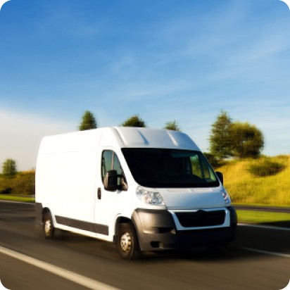 A large, white delivery van driving down a rural highway.