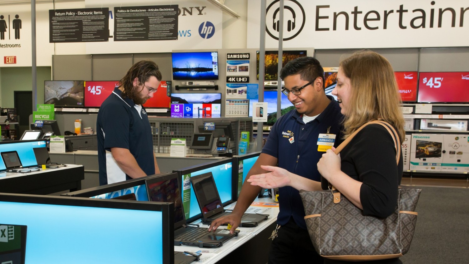 A potential customer talking to a Walmart associate pointing at a laptop