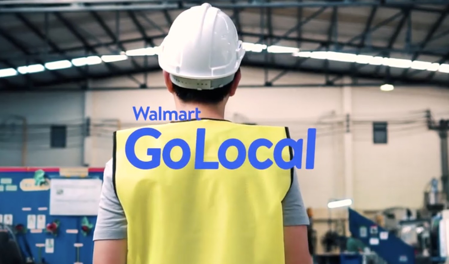 The back profile of a male associate wearing a yellow vest with text Walmart Go Local