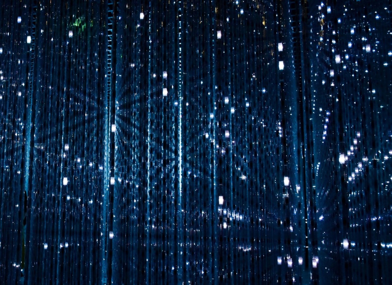 Image shows vertical blue light strands with numerous small white lights reflected in a mirror.